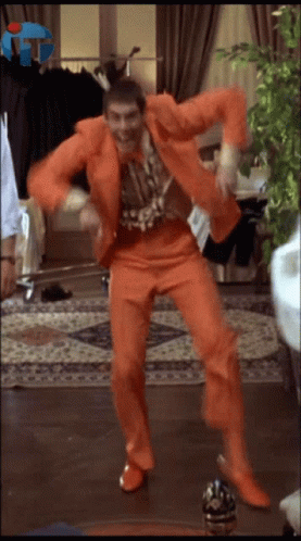 Man In Orange Suit Dancing In Front Of FTT Sign GIF