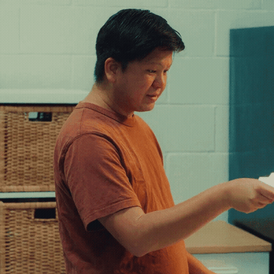 A Man In An Orange T-Shirt Is Holding A Piece Of Paper GIF