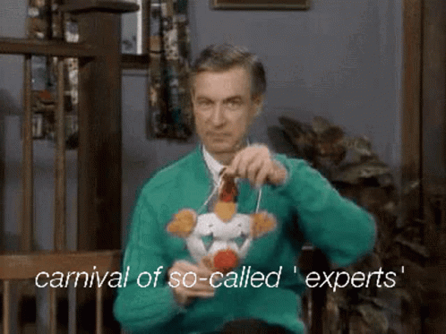 A Man In An Ugly Christmas Sweater Is Holding A Stuffed Chicken On A String . GIF