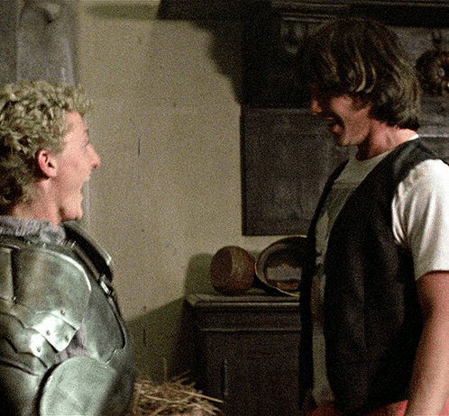 A Man In Armor And A Man In A White Shirt Are Laughing GIF
