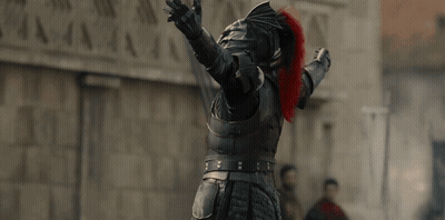 A Man In Armor Has His Arms Outstretched In Front Of A Stone Wall GIF