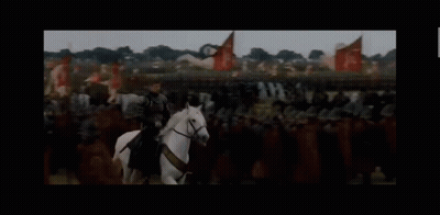 A Man In Armor Is Riding A White Horse In Front Of A Crowd Of People . GIF