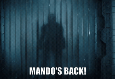 A Man In Armor Is Standing In A Dark Room With The Words Mando 'S Back On The Bottom GIF