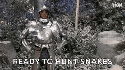 A Man In Armor Is Standing In A Snowy Forest With His Hands On His Hips . GIF