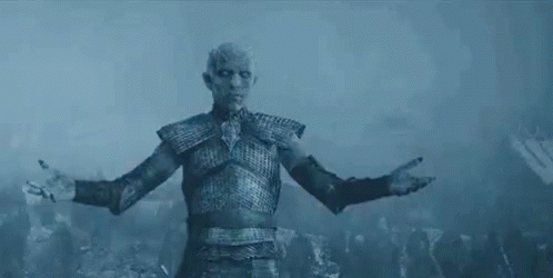 A Man In Armor Is Standing In Front Of A Crowd Of People In A Dark Room . GIF