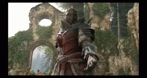 A Man In Armor Is Standing In Front Of A Ruined Building . GIF