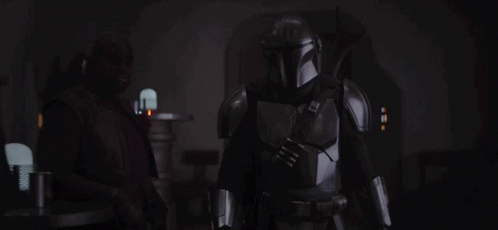 A Man In Armor Is Standing In The Dark GIF