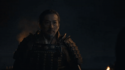 A Man In Armor Is Standing In The Dark With A Torch In His Hand . GIF