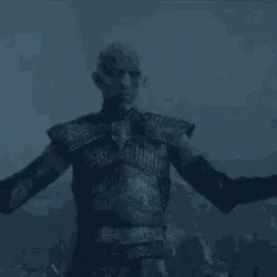 A Man In Armor Is Standing In The Dark With His Arms Outstretched In The Air . GIF