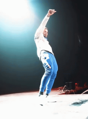 A Man In Blue Sweatpants Is Dancing On Stage GIF