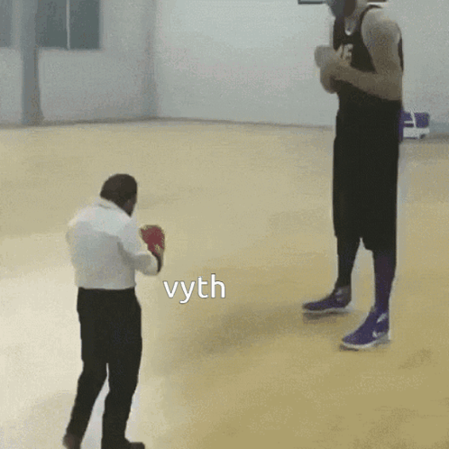 A Man In Boxing Gloves Stands Next To A Man In A Basketball Uniform And The Word Vyth Is On The Floor GIF