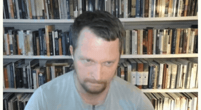 A Man In Front Of A Bookshelf With A Book Titled ' A Brief History ' On It GIF