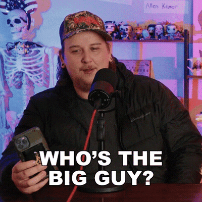 A Man In Front Of A Microphone Is Holding A Cell Phone And Says Who 'S The Big Guy GIF