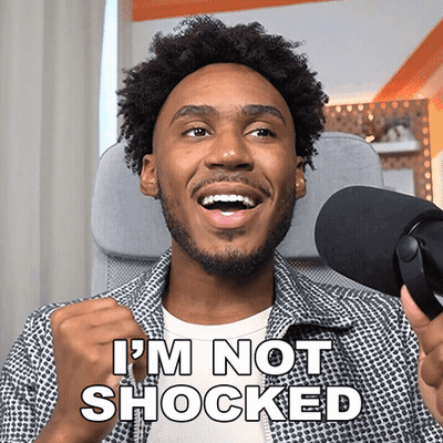 A Man In Front Of A Microphone With The Words I 'M Not Shocked Above Him GIF
