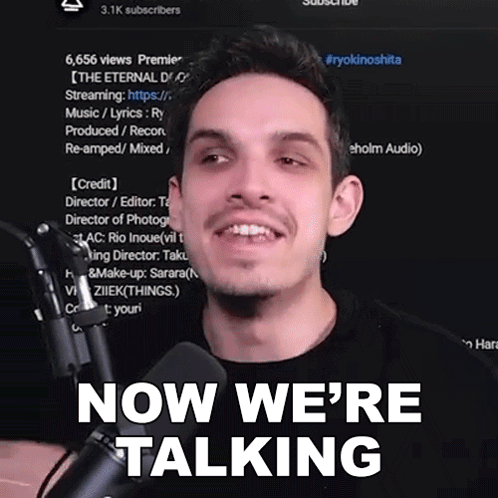 A Man In Front Of A Microphone With The Words Now We 'Re Talking Behind Him GIF