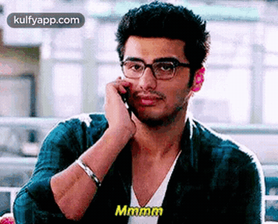 A Man In Glasses Is Talking On A Cell Phone . GIF