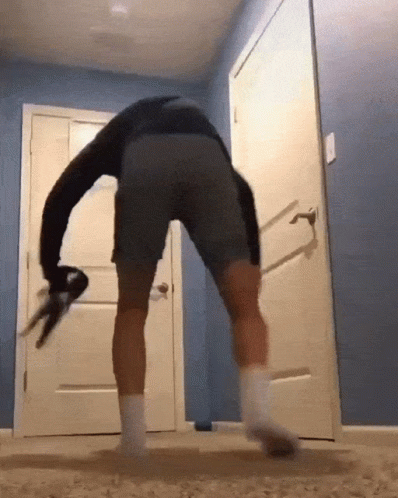 A Man In Gray Shorts And White Socks Is Dancing In Front Of A White Door GIF