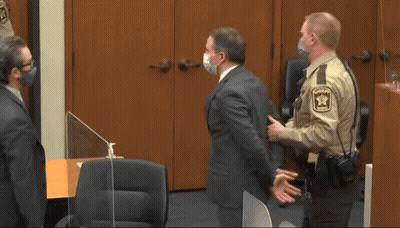 A Man In Handcuffs Is Escorted By Two Police Officers In Front Of A Door That Says C1874 GIF