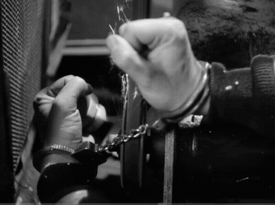 A Man In Handcuffs Is Trying To Unlock A Door GIF
