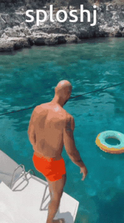 A Man In Orange Shorts Is Jumping Into A Body Of Water With The Word Splashj Above Him GIF