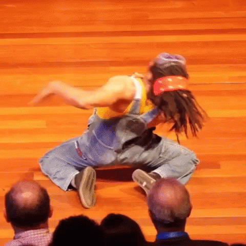 A Man In Overalls And A Bandana Is Dancing On A Wood Floor GIF