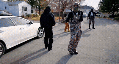 A Man In Overalls Is Walking Down A Street GIF