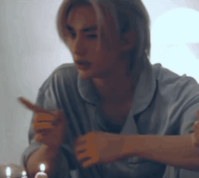 A Man In Pajamas Is Sitting At A Table With Candles In His Hand . GIF