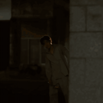 A Man In Pajamas Is Walking Down A Street At Night GIF