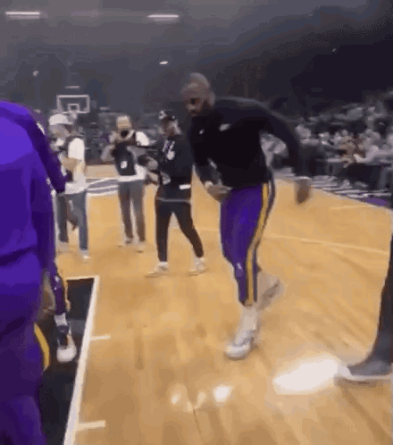A Man In Purple Pants Is Dancing On A Basketball Court GIF