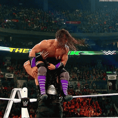 A Man In Purple Socks Is Being Lifted In The Air By Another Man GIF