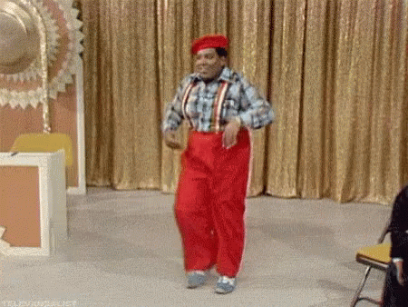 A Man In Red Pants Is Dancing On A Stage In Front Of A Gold Curtain . GIF