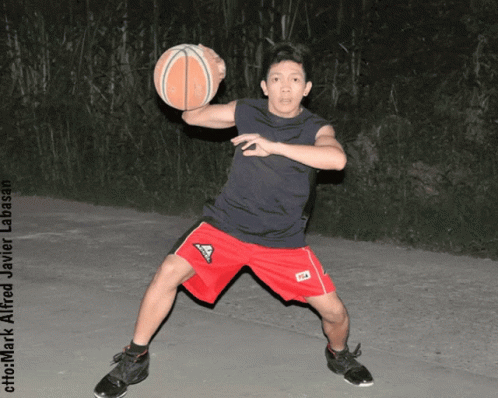 A Man In Red Shorts Is Holding A Basketball In His Hands GIF