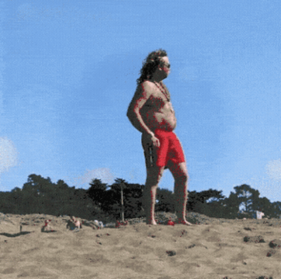 A Man In Red Shorts Is Standing On A Beach GIF