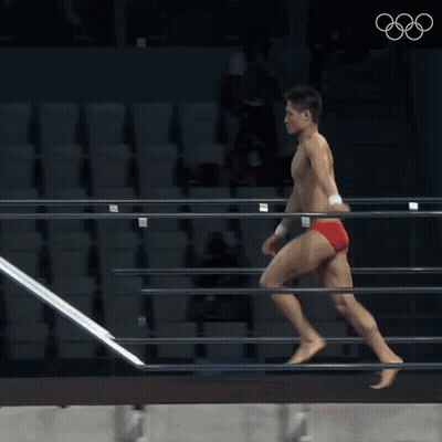 A Man In Red Swim Trunks Is Diving Into A Pool At The Olympics GIF