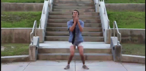A Man In Shorts And A Tie Is Standing On A Set Of Stairs GIF