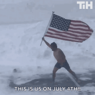A Man In Shorts Is Holding An American Flag In The Snow GIF