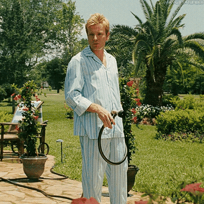 A Man In Striped Pajamas Is Holding A Hose In His Hands GIF