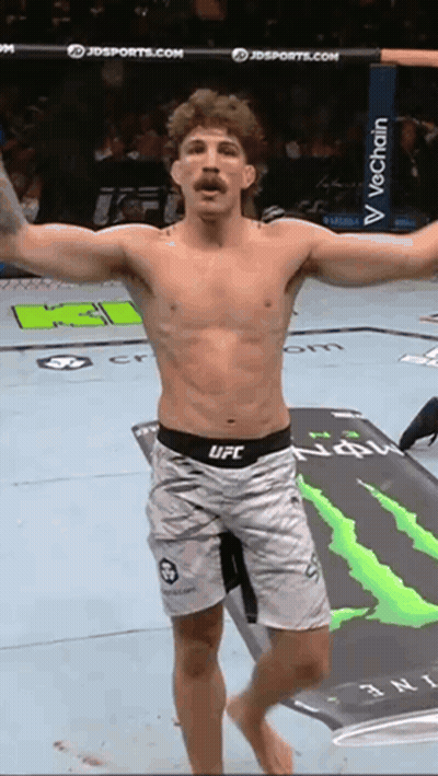 A Man In Ufc Shorts Is Standing On A Mat With A Monster Energy Logo In The Background GIF