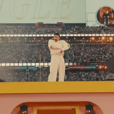 A Man In White Stands On A Stage In Front Of A Crowd And A Sign That Says ' Louisville ' On It GIF