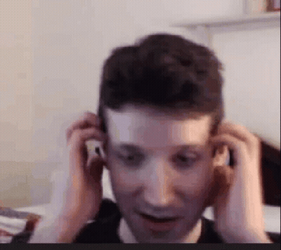 A Man Is Adjusting His Ear Buds While Sitting In Front Of A Computer Screen . GIF