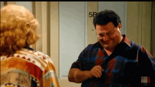 A Man Is Adjusting His Tie While Standing Next To A Woman In Front Of A Door That Says 5B . GIF
