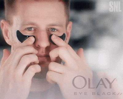 A Man Is Applying Black Eye Patches From Olay Eye Black GIF