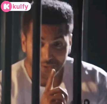 A Man Is Behind Bars With His Finger On His Lips GIF