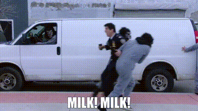 A Man Is Being Held By A Police Officer In Front Of A Van . GIF