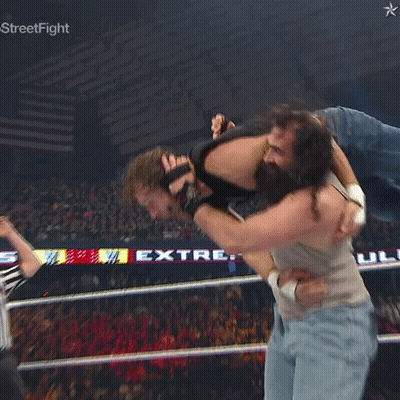 A Man Is Being Lifted In The Air By Another Man In A Wrestling Ring With A Star On The Bottom Right GIF
