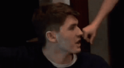 A Man Is Being Punched In The Face By Another Man While Sitting Down . GIF