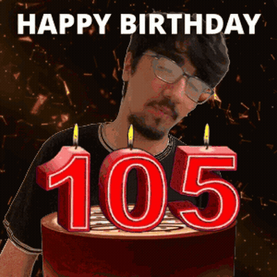 A Man Is Blowing Out Candles On A Birthday Cake With The Number 105 On It GIF