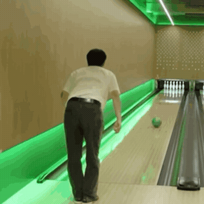 A Man Is Bowling In A Bowling Alley With Green Lights GIF