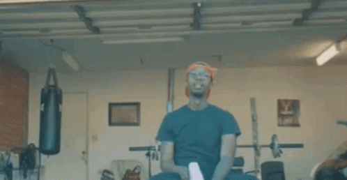 A Man Is Boxing In A Garage With A Red Light Coming Out Of His Eyes . GIF