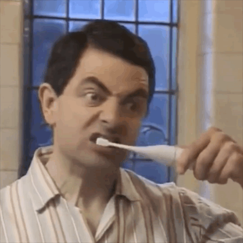 A Man Is Brushing His Teeth With A Toothbrush In A Bathroom . GIF